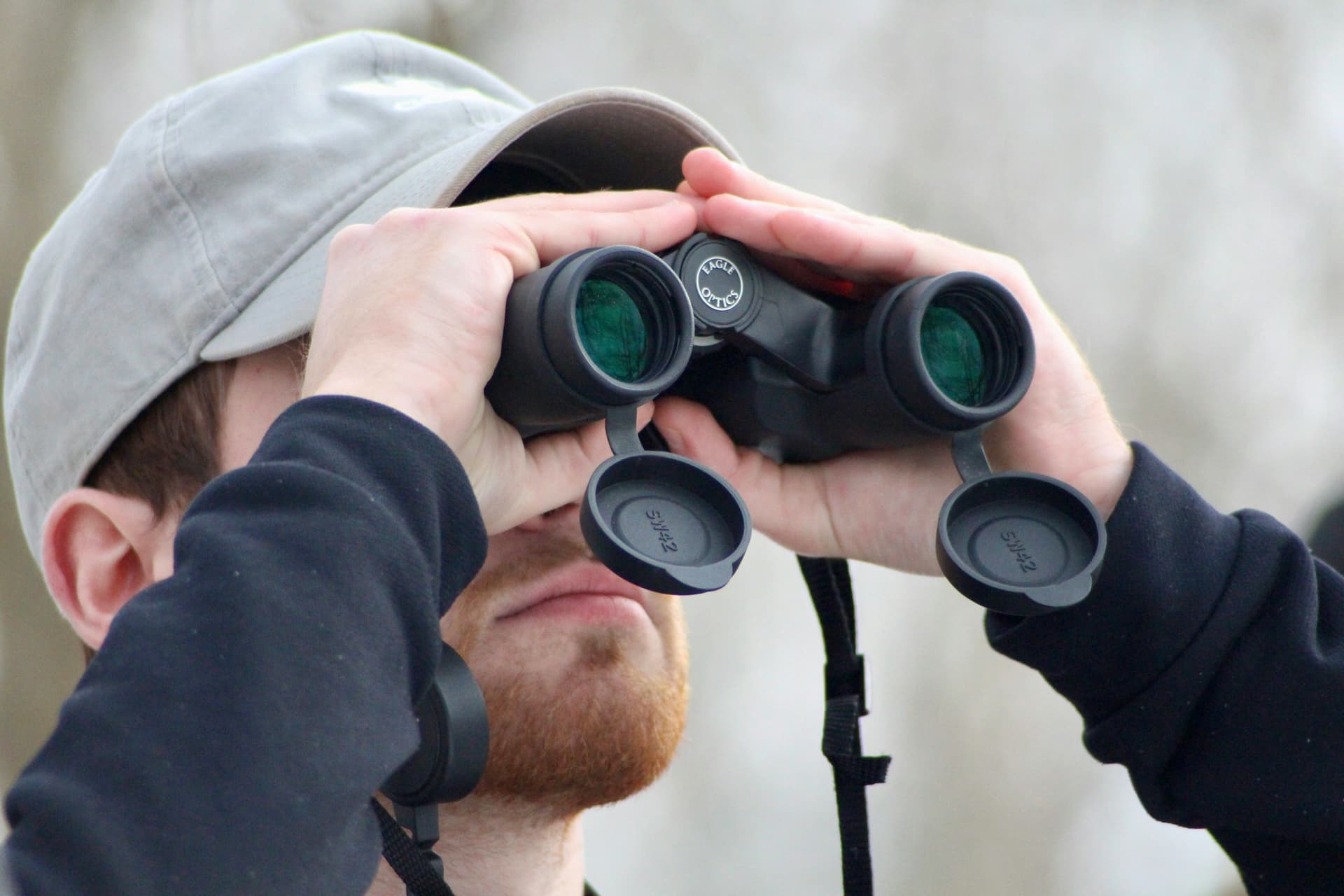 A hunter glassing a hillside through binoculars at first light
